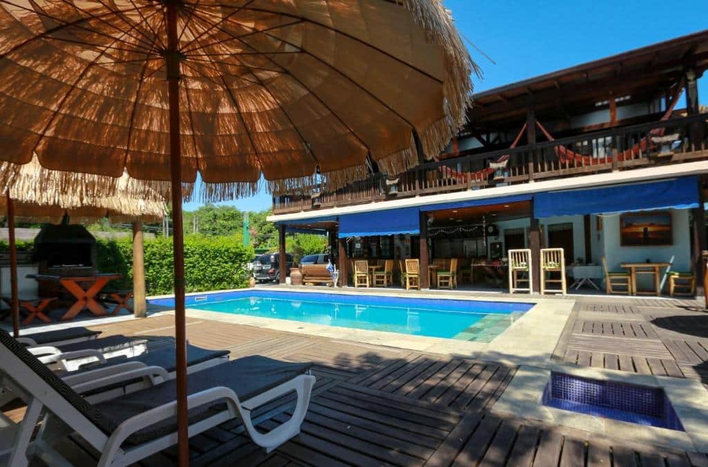 Vista da piscina da Pousada Pura Vida Maresia durante o dia com cadeiras com guarda-sóis perto da piscina. Representa pousadas na praia de Santiago.