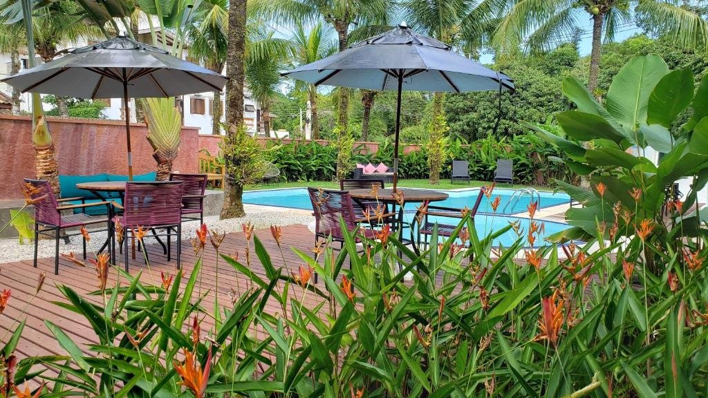 Vista da piscina da Pousada Toca da Praia com cadeira e mesa a frente ao fundo a piscina. Representa pousadas na praia de Santiago.