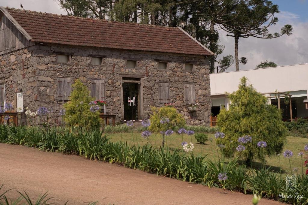 Pousada Cantelli no Vale dos Vinhedos com prédio antigo todo feito de pedras e jardins em frente