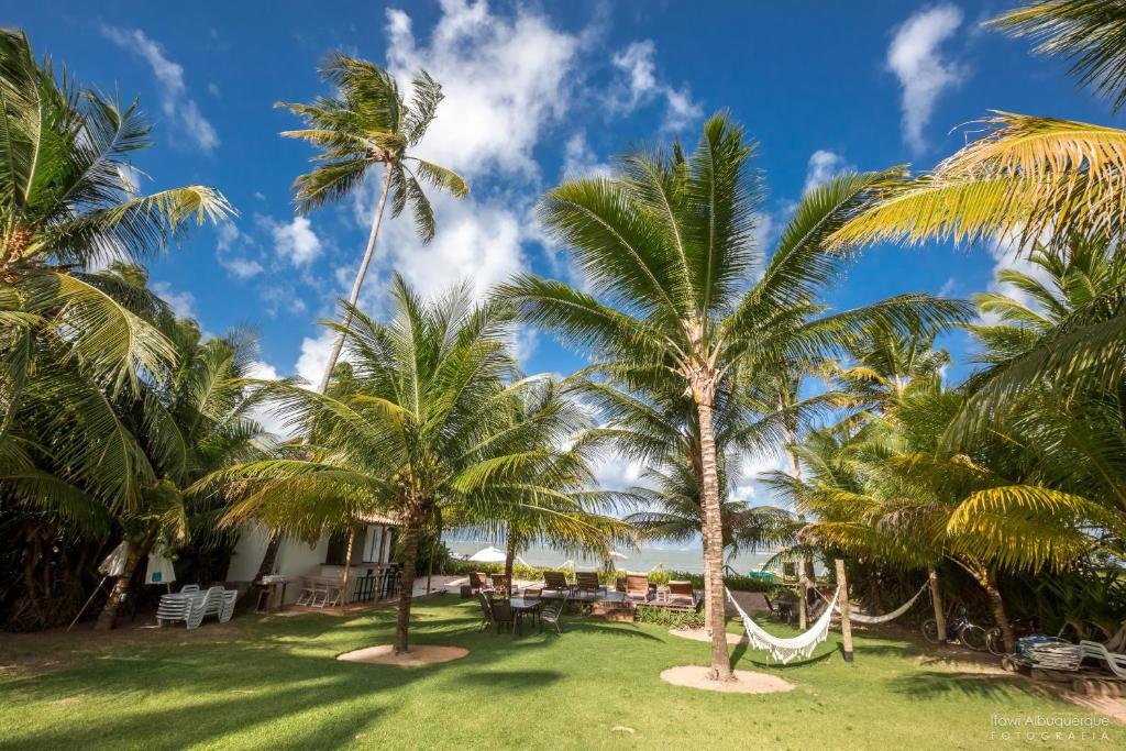 Gramado à beira-mar com redes, árvores e espreguiçadeiras com vista e acesso ao mar da Pousada Casotas, em Alagoas