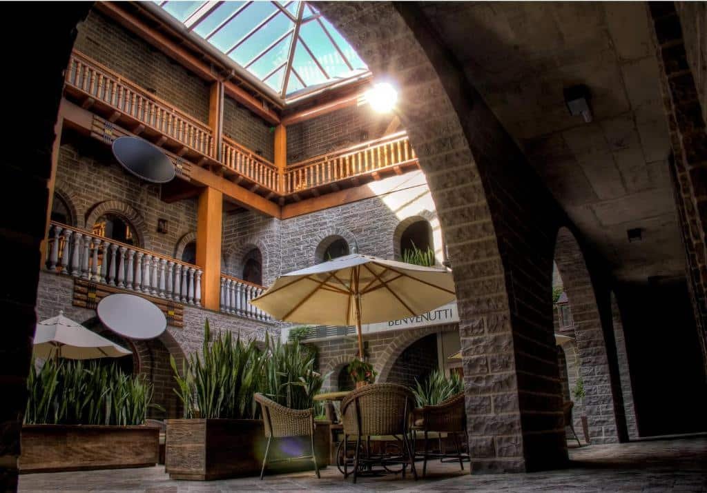 Área interior central na Pousada Castello Benvenutti, com teto de vidro por onde passa a luz do sol