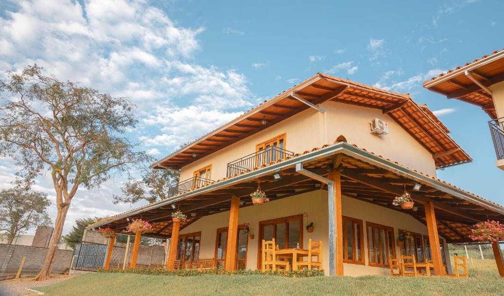 Pousada Cheiro da Terra, uma construção de dois andares em estilo rústico e bem nova, com janelas e portas de madeira, com sacadas no andar superior e um jardim ao redor da propriedade
