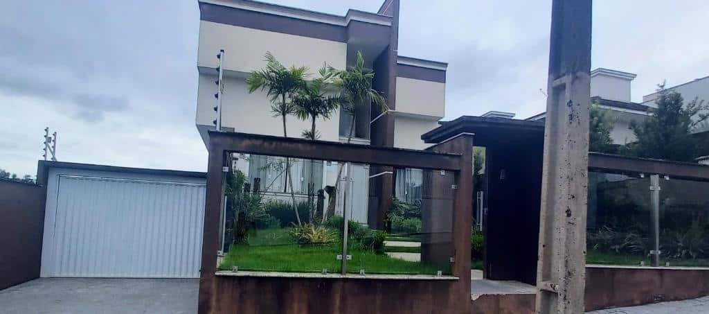fachada da Pousada Floresta mostrando um jardim na entrada, ao lado de uma porta de garagem branca.