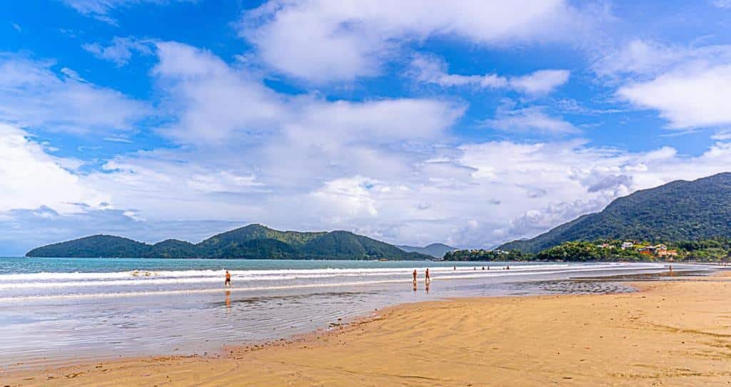 Praia da Enseada em Ubatuba, faixa muito extensa de areia, muitas montanhas e ilhotas ao redor, mar calmo
