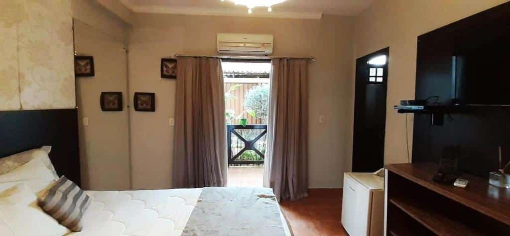 quarto da Pousada Villa Guimaraes com uma cama de casal com varanda privativa com vista para o jardim