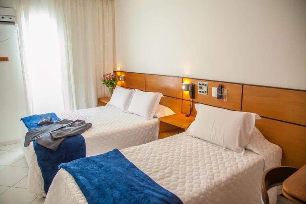 Quarto do Atlantico Inn Apart Hotel com uma varanda com cortinas, uma cama de solteiro e uma de casal