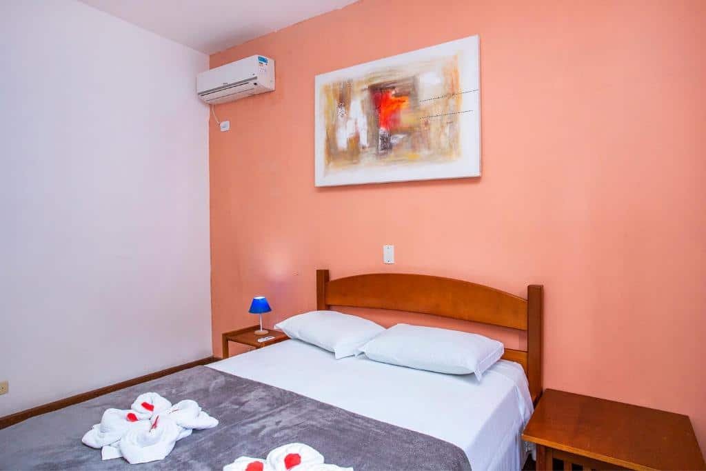 Quarto da Pousada Villa Blu Maresias com cama de casal e duas cômodas de madeira ao lado.