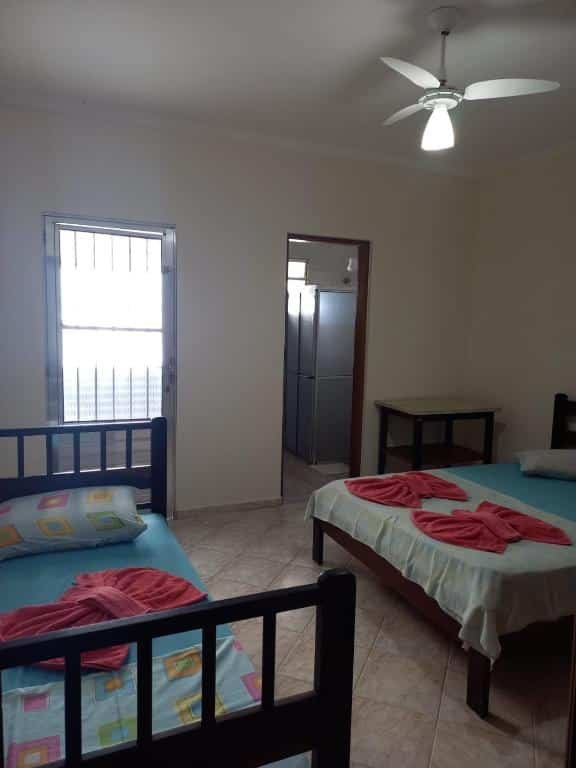 Quarto com cama de solteiro no lado esquerdo, cama de casal no lado direito e porta para o banheiro na parede ao lado da cama de casal. Imagem para ilustrar o post pousadas em Mongaguá.