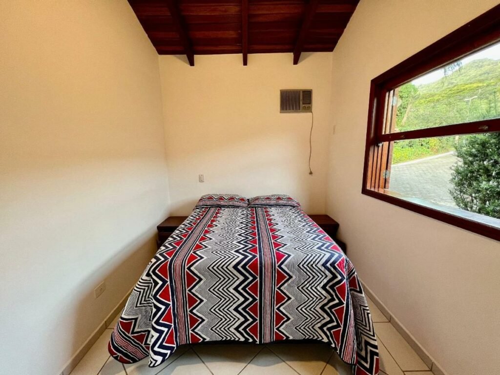Quarto da Casa com piscina privativa no Paúba um Vilarejo com cama de casal no centro do quarto e uma cômoda em cada lado da cama. Representa airbnb na praia de Santiago.