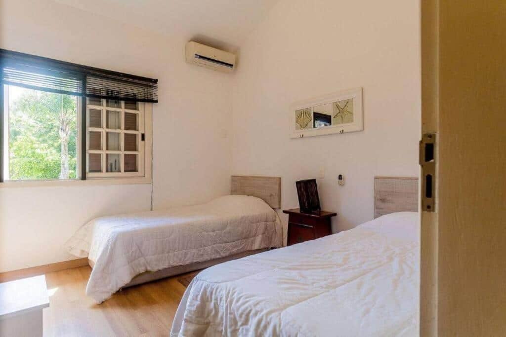 Quarto da Casa em Condomínio Pé na Areia na Praia do Engenho com duas cama de solteiro uma de casa lado do ambiente com uma cômoda no meio. Representa airbnb na praia do Engenho.