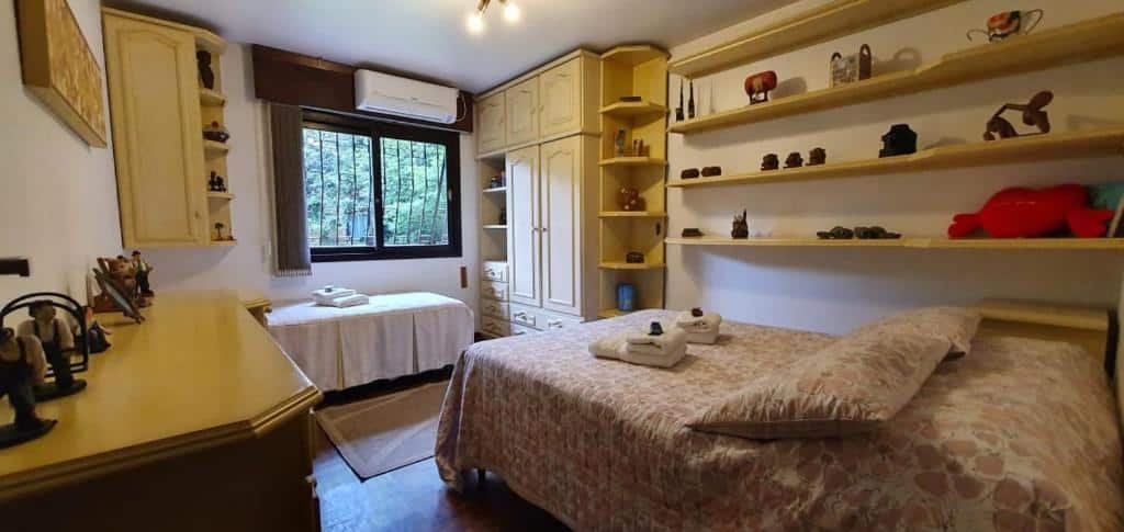 Quarto amplo na CASA GOLDONI GRAMADO 3 Quartos, duas camas de solteiro, muitas prateleiras e um armário, uma janela, um ar-condicionado, para representar airbnb em Gramado