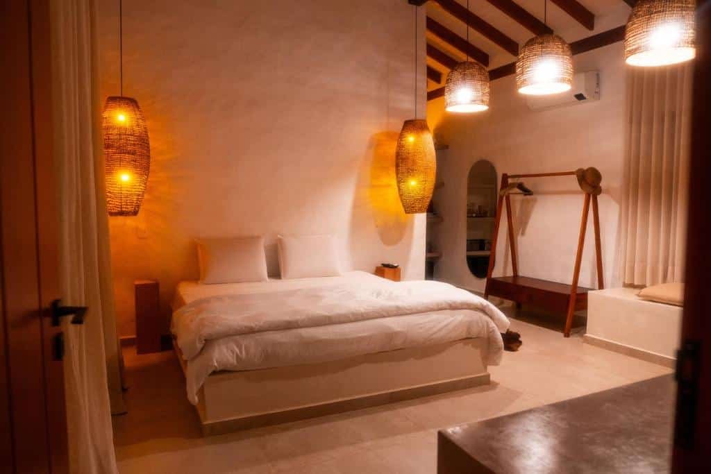 Quarto do Nai com cama de casal no centro do quarto e em cada lado da cama uma luminária pendurada no teto em cada lado. Representa airbnb na praia de Santiago.
