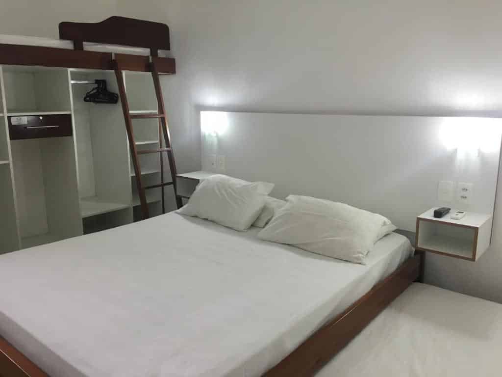 Quarto no DiPietro Home, uma cama de casal, iluminação indireta, um armário de conceito aberto, para representar pousadas na Praia do Tenório