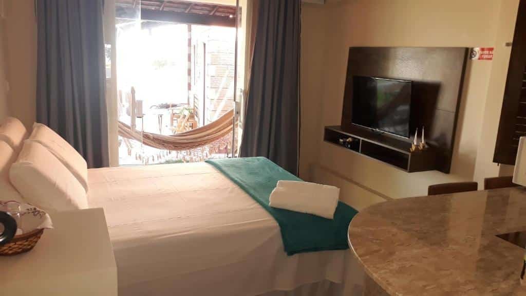 Quarto do Parque dos Coqueiros, com uma cama de casal, ma TV e uma varanda na frente do quarto com uma rede