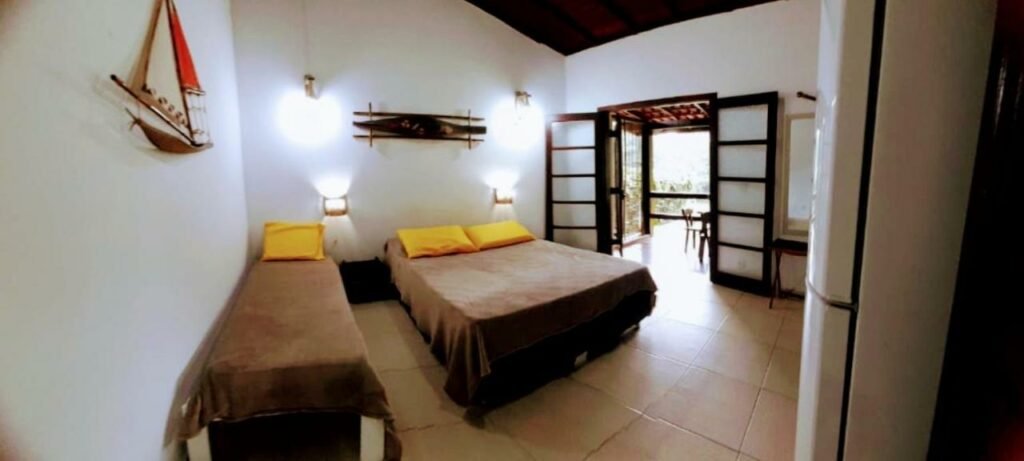 Quarto do Flat na Jureia – 30 MT da Praia com uma cama de solteiro do lado direito da imagem e do lado esquerdo uma cama de casal. Representa airbnb na praia da Juréia.