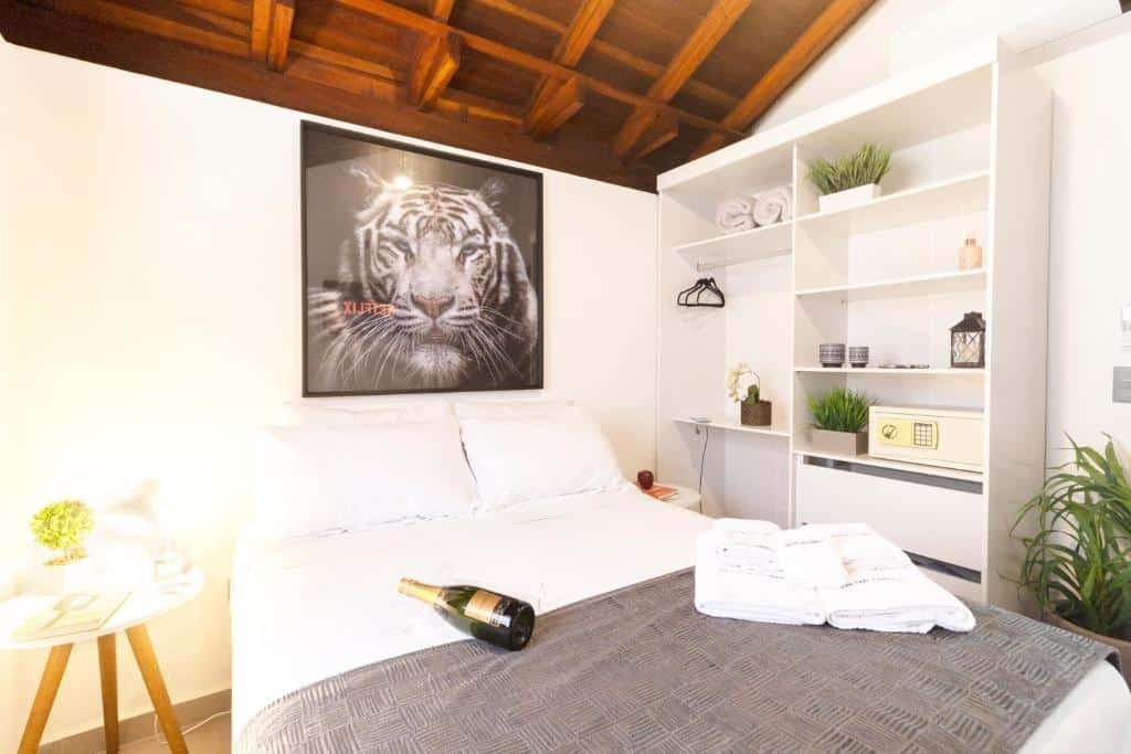 Quarto do Flats Una’s Corner – Novos – Ar Condicionado com cama de casal do lado esquerdo da imagem no centro do quarto com uma cômoda em cada lado.