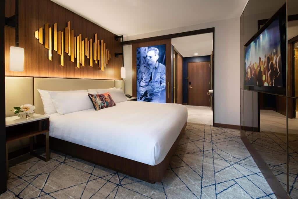 quarto do Hard Rock Hotel New York hotel perto da times square com uma cama de casal à esquerda, um quadro de um cantor no lado direito da imagem e uma televisão de tela plana em frente a cama, pendurada na parede.