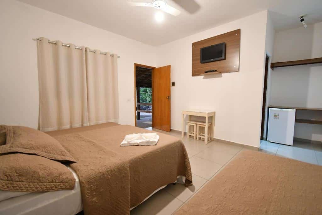 Quarto no Hotel Morro De Santo Agostinho com uma cama de casal e uma de solteiro, com uma televisão, um armário de conceito aberto e um frigobar