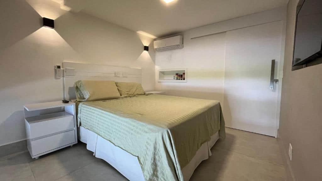 Quarto do Lindo Loft em Condomínio Praia Barra do Una com cama de casal do lado esquerdo da imagem no centro do quarto em cada lado da ama uma cômoda. Representa airbnb na praia do Engenho.
