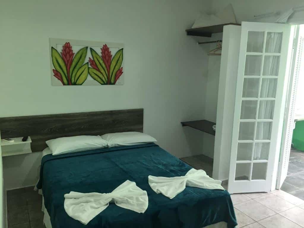 Quarto da Marencanto Pousada, uma cama de casal, uma sacada e um quadro sob a cama