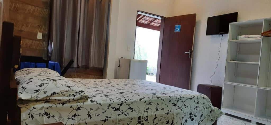 Quarto da Pousada das Pedras com cama de casal, uma comada a frente e TV.