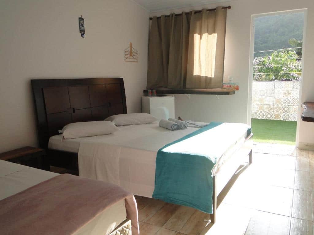 Quarto da Pousada Estrela Mare com cama de solteiro do lado direito e do lado esquerdo cama de casal, com frigobar.