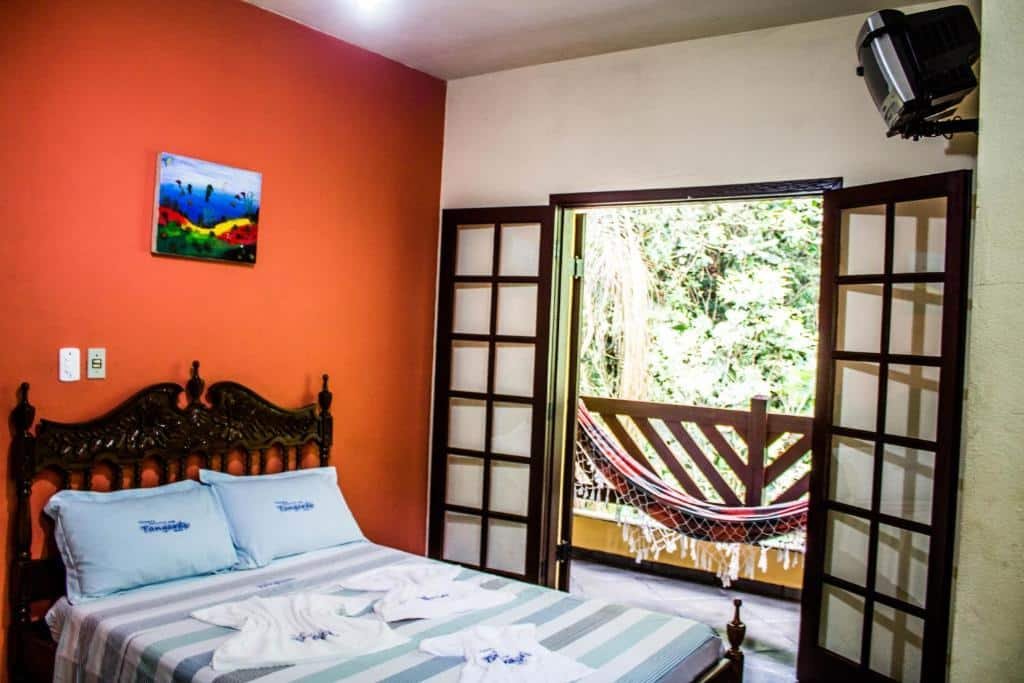 Quarto da Pousada Recanto dos Tangaras com cama de casal, varanda com rede.