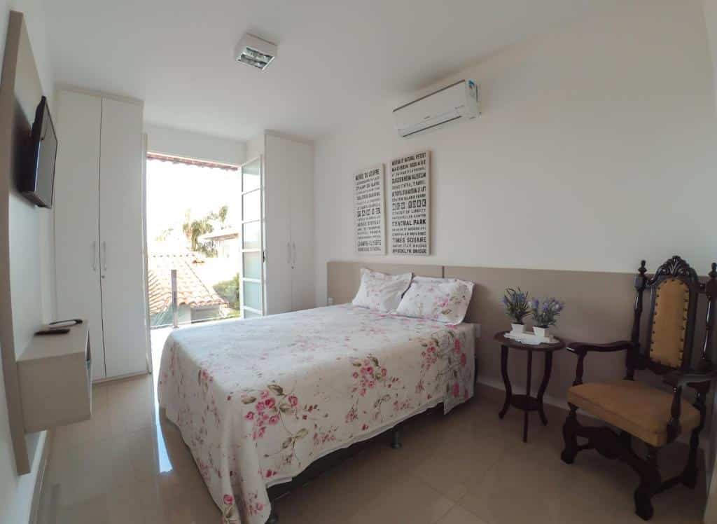 Quarto na Pousada Suítes do Lago, uma cama de casal, um ar-condicionado, uma televisão, uma varanda, dois armários e uma cadeira, para representar pousadas em Escarpas do Lago