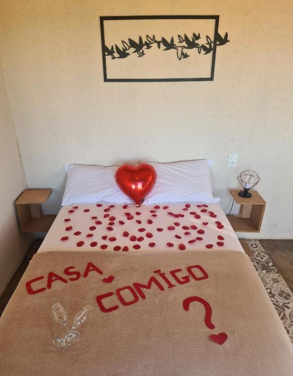 cama de casal enfeitada com pétalas de rosa vermelhas formando os dizeres "casa comigo?