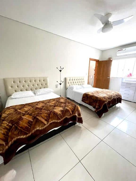 Quarto do Recanto da Ivete com uma cama de casal do lado esquerdo da imagem e outra cama de casal do lado direito. Representa airbnb na praia da Juréia.