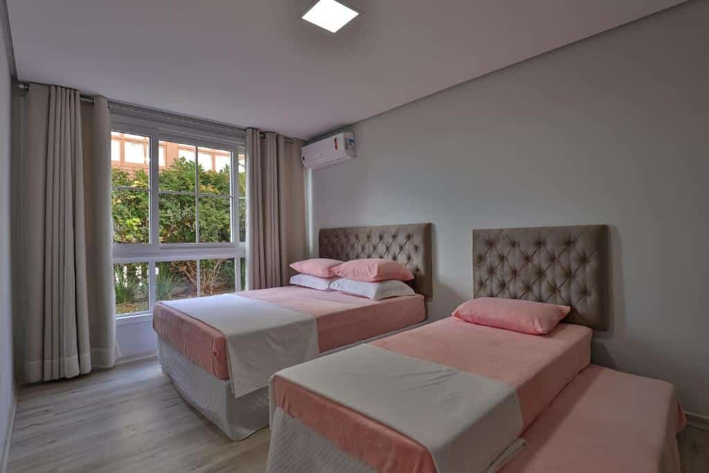 Um quarto amplo no RESIDENCIAL LONDON ALPHAVILLE AP 104, uma cama de casal e uma de solteiro, uma sacada ampla com cortina, um ar-condicionado, para representar airbnb em Gramado