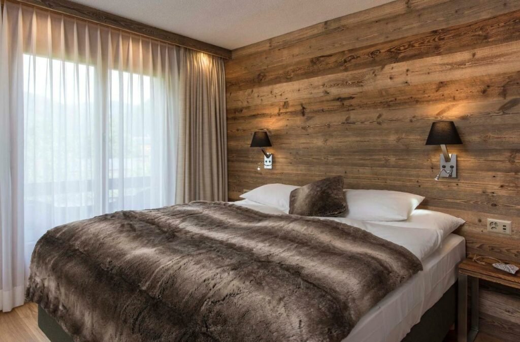 Quarto do Salzano Hotel com cama de casal do lado direito da imagem e em cada lado da cama uma cômoda.