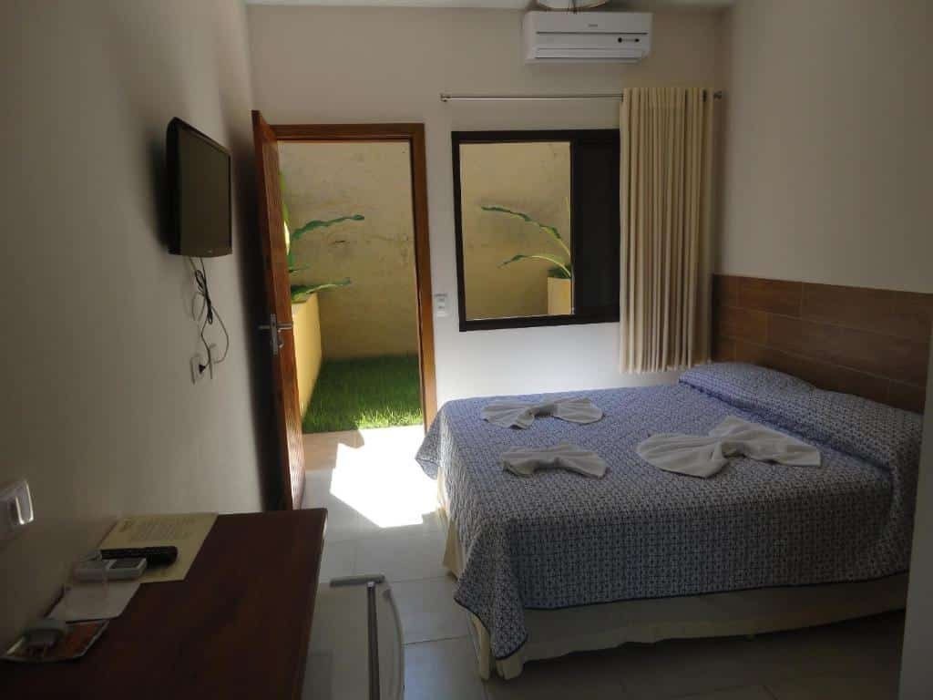 Quarto da Pousada Samburá com cama de casal, TV em frente a cama presa na parede e uma cômoda do lado direito.