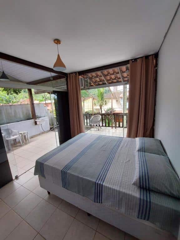 Quarto do Solaris do Una com cama de casal do lado direito em frente a cama uma porta de vidro que dá acesso a varanda.