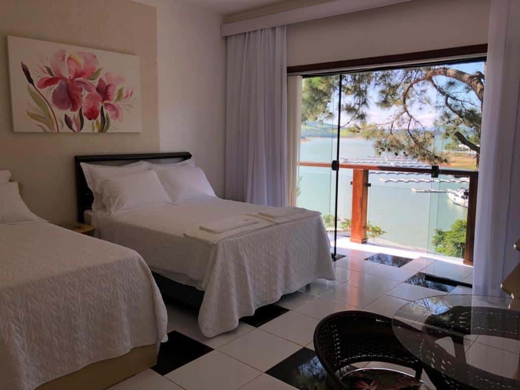 Quarto no Solarium de Escarpas Suítes, uma cama de casal e uma de solteiro, com uma varanda dando vista para o lago, para representar pousadas em Escarpas do Lago