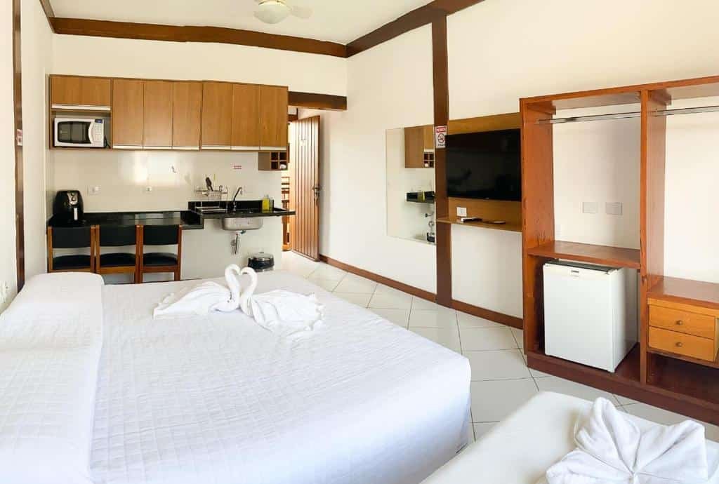 Suíte da Suítes Trilha do Sol, uma cama de casal, uma de solteiro, armários, frigobar, um espelho, uma pequena cozinha, para representar pousadas na Praia do Tenório