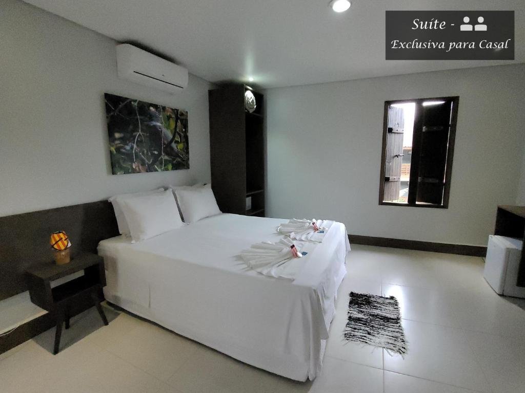 Quarto da Pousada Tartarugas de Paúba com cama de casal, duas cômodas ao lado da cama, ar-condicionado acima da cama e cômoda do lado esquerdo do quarto.