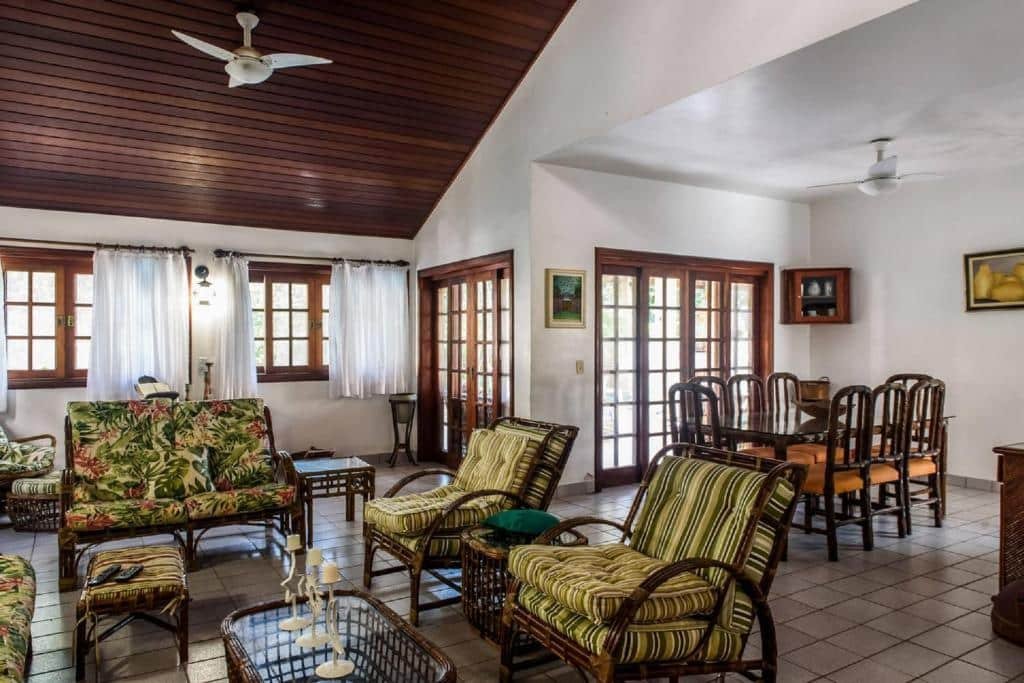 sala ampla repleta de janelas e cadeiras na Casa Riviera um airbnb na Riviera de São Lourenço