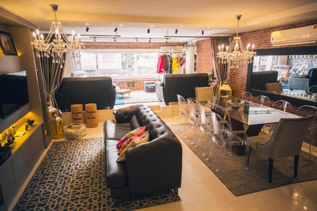 Sala de estar e jantar do Ap de Cinema! No centro!, local decorado em estilo vintage, um sofá de couro, uma televisão, uma mesa ampla com dez lugares, um lustre, um ar-condicionado, um espelho e uma janela ampla com vista para a rua