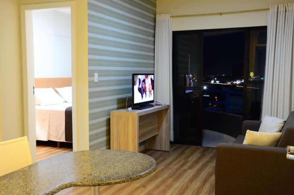 Sala do quarto Classe Apart Hotel com sofá, TV em Feira de Santana.