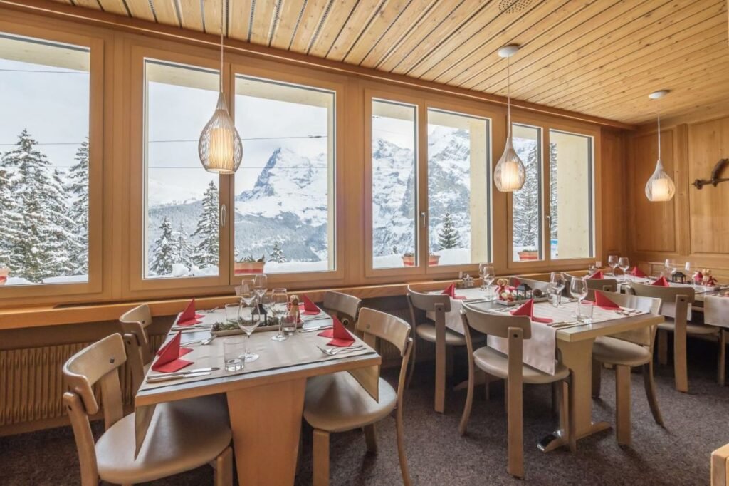 Sala de café da manhã do Hotel Alpenblick Mürren com cadeiras e mesas no ambiente.