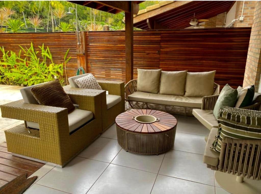 Área de lazer da Casa Pé na Areia com sofá e poltronas no ambiente.