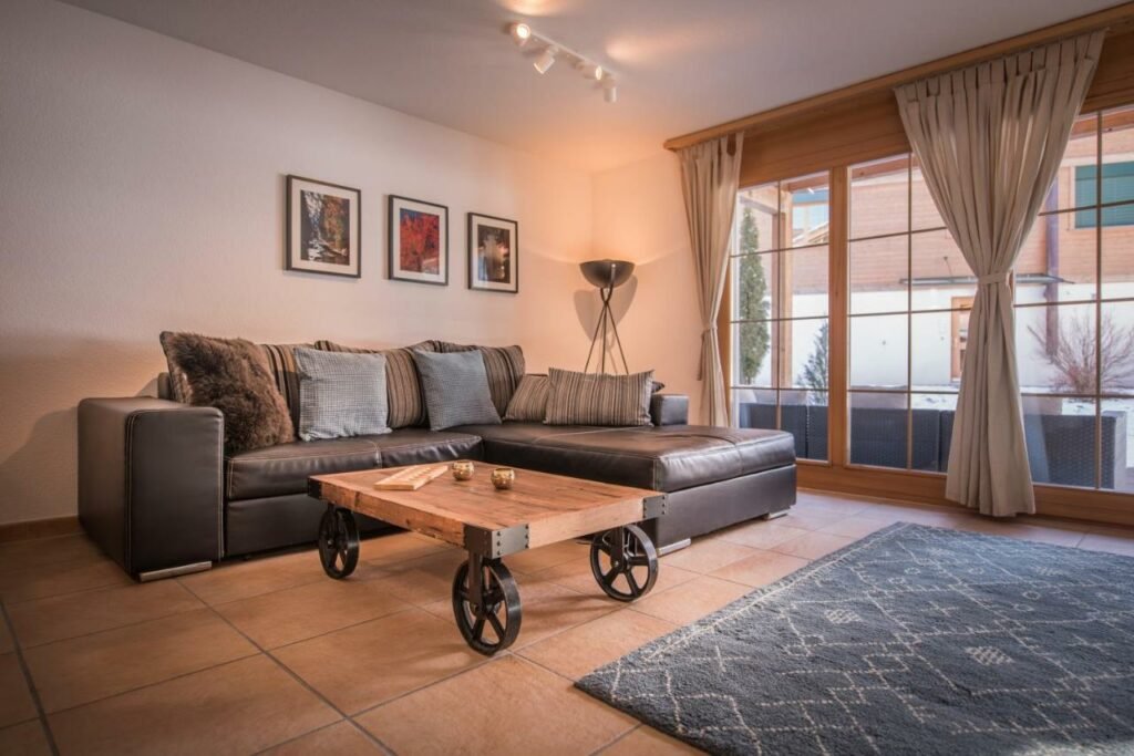 Sala de estar do Luterbach com mesa de centro do lado esquerdo da imagem a frente e no fundo um sofá. Representa hotéis em Lauterbrunnen.