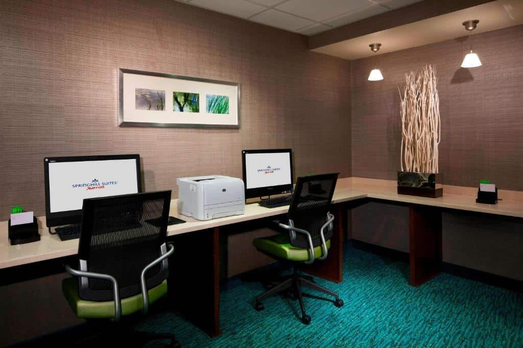 Imagem de uma sala de reuniões no SpringHill Suites Newark Airport. A sala é espaçosa, com uma grande mesa retangular rodeada por cadeiras confortáveis. Na parede oposta à mesa, há uma tela de projeção. O ambiente é iluminado por luminárias no teto, proporcionando uma iluminação adequada para reuniões. O SpringHill Suites Newark Airport é um dos hotéis perto do aeroporto de Newark.