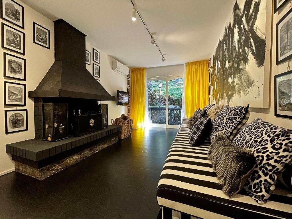 Sala de estar do Luar de Inverno 203 - Apartamento 3 suítes Gramado, tudo decorado em preto e branco, com uma sacada, uma lareira, um ar-condicionado e tudo decorado