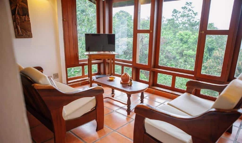 Sala de estar do Refúgio Toque Toque Chalés com sofá a frente uma mesa de centro e ao fundo do lado esquerdo da imagem uma cômoda com TV.