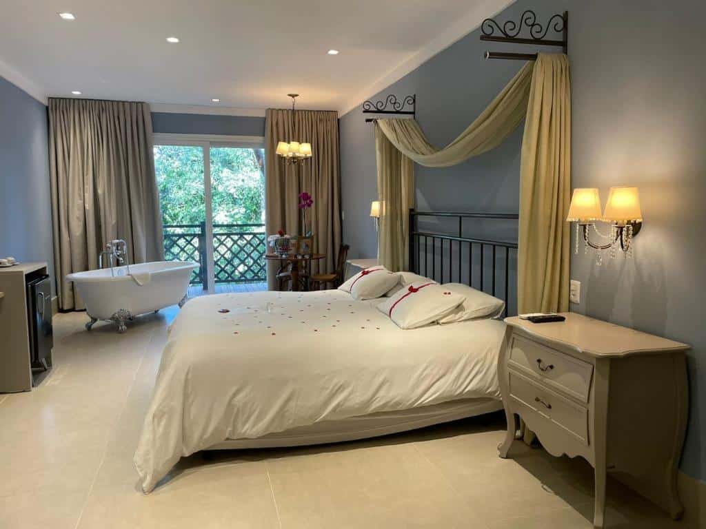 quarto da Pousada Casa da Quineira com uma cama de casal, uma varanda com vista para a natureza e uma banheira ao fundo