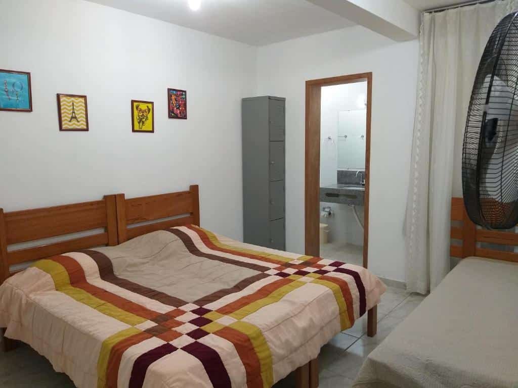 Quarto do Thiferer Hostel. A cama de casal está no lado esquerdo do quarto e a cama de solteiro no lado direito. Ainda no lado direito está a porta do banheiro e um pequeno armário. Imagem para ilustrar o post hotéis em Viçosa.