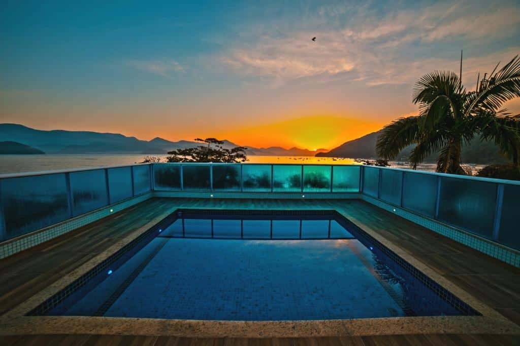 Vista da piscina do Ubatuba Praia Hotel, em direção da praia, montanhas e pôr-do-sol