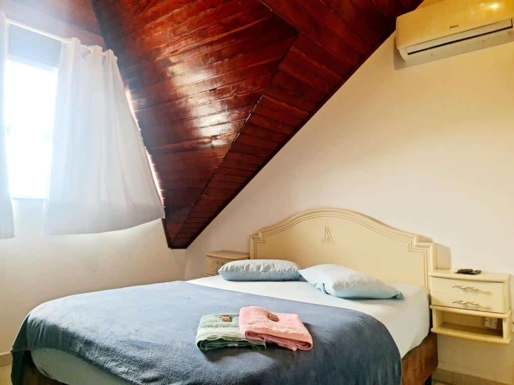 quarto do Valentina Ramos Pousada em Joinville com uma cama de casal no centro da suíte. No canto superior direito há um ar-condicionado preso à parede.